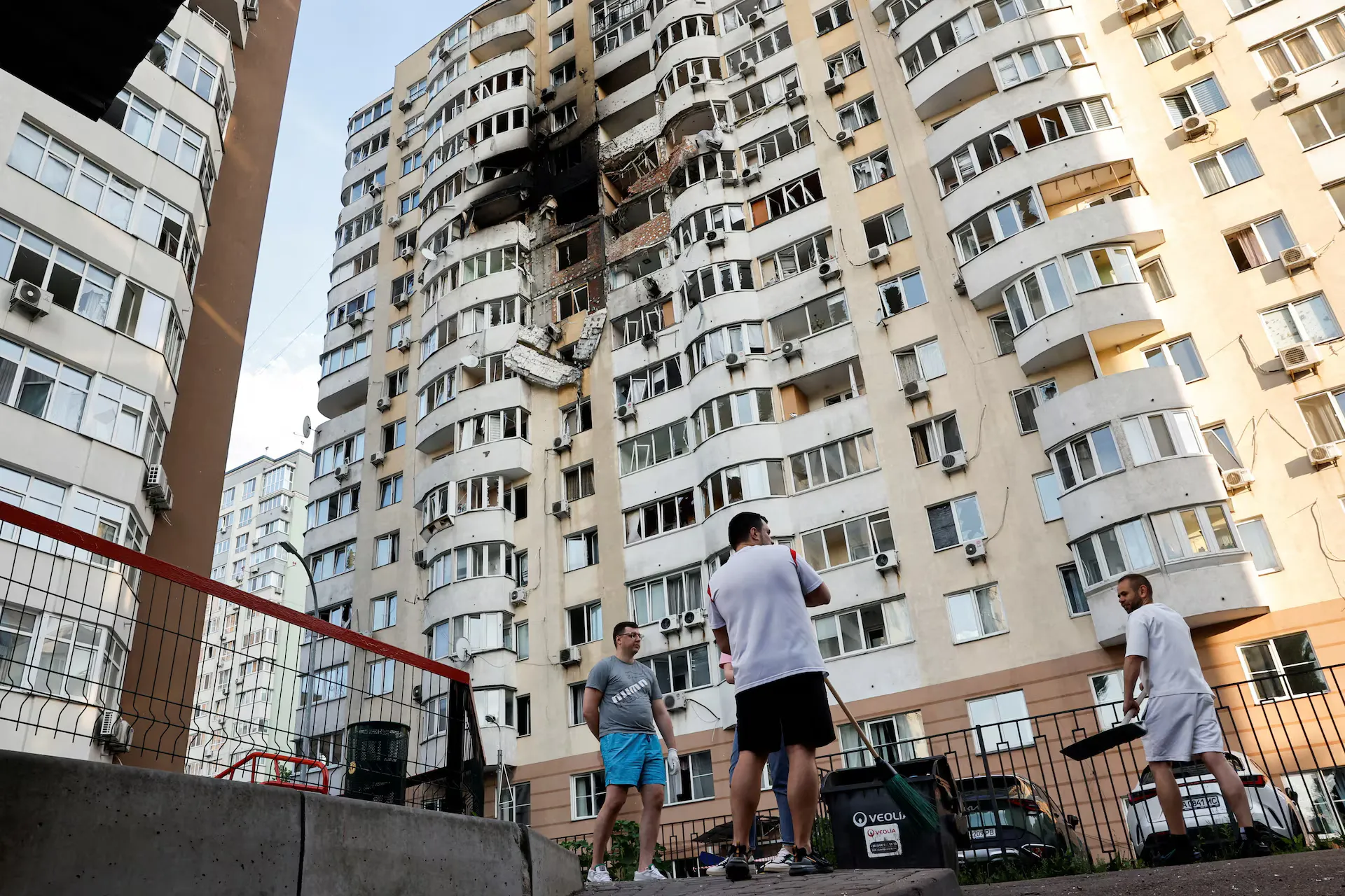 Місцеві жителі прибирають після того, як російський безпілотник влучив у житловий будинок під час російського нападу на Україну, Київ, Україна, 6 червня 2025 року